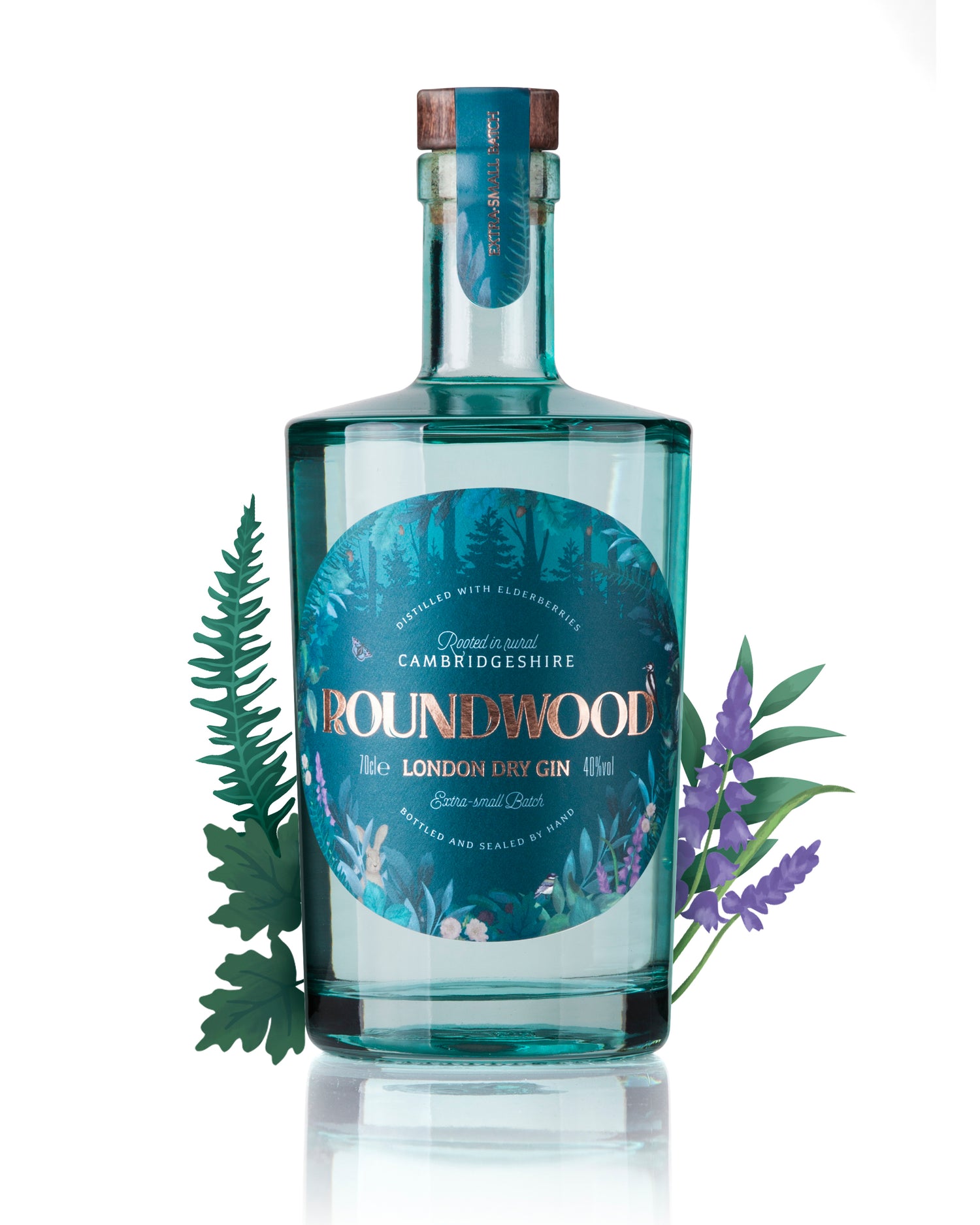 Roundwood Gin striking teal blue bottle, with illustrative botanical woodland label. Label shows copper foiled heading. Bottle displayed with decorative artwork of foxgloves and leaves